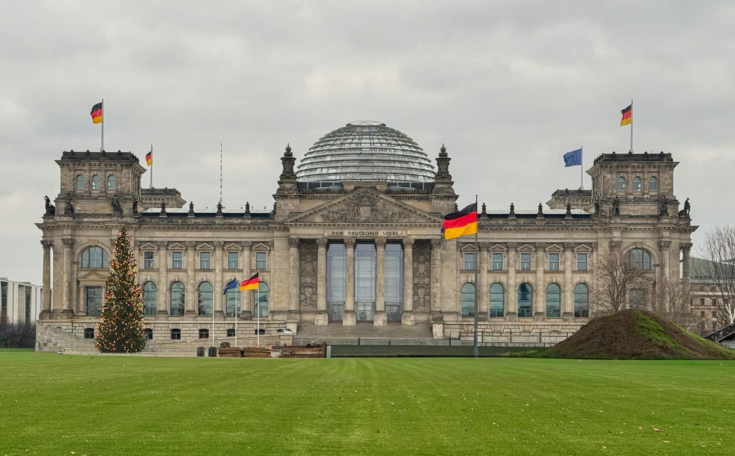 Reichstag building in Berlin, Germany with flags and Christmas tree in winter.