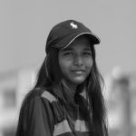 Black and white portrait of a teenager wearing a casual outfit and cap outdoors, exuding a modern urban vibe.